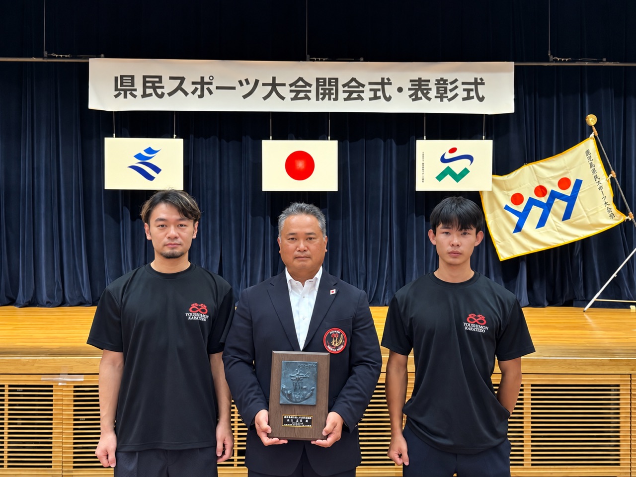 県民スポーツ大会開会式・表彰式の会場で顕彰の楯を手にする宗師と門下生