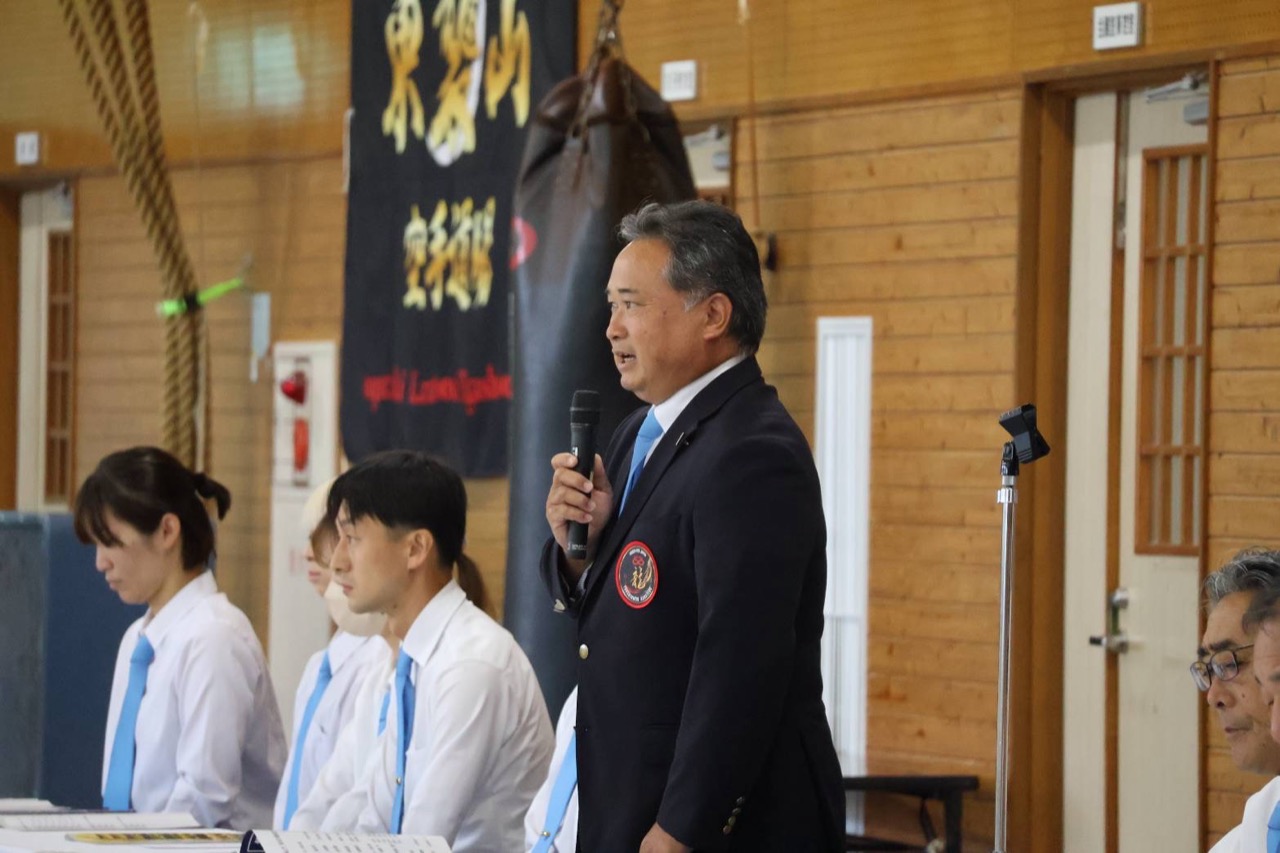 開会式でマイクを手に選手へ言葉を述べる大会役員