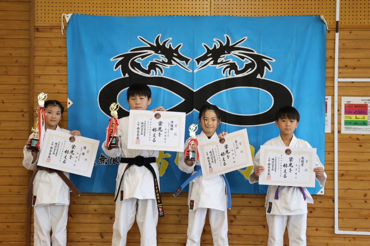 賞状とトロフィーを手にする小学生の入賞者