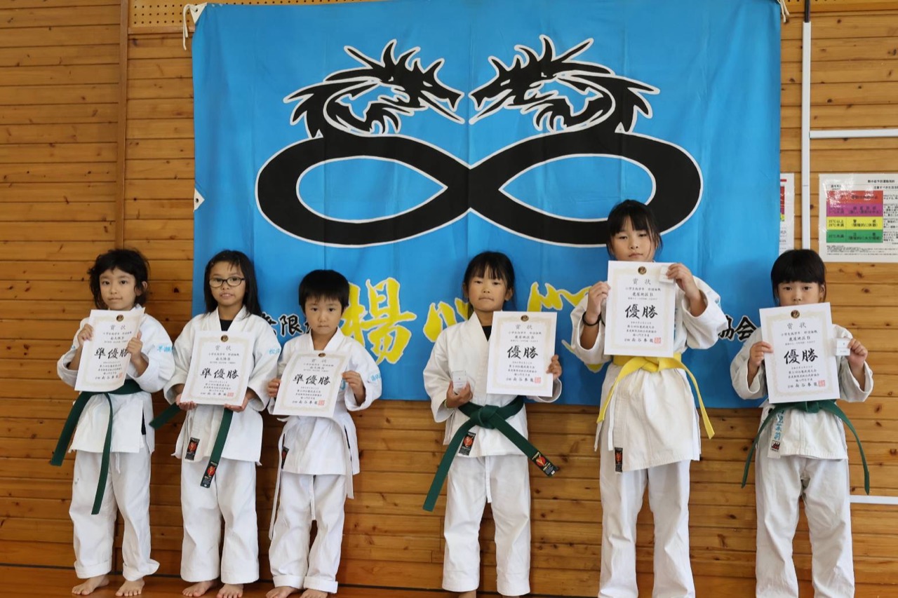 賞状を手に道場旗の前へ並ぶ低学年の入賞者