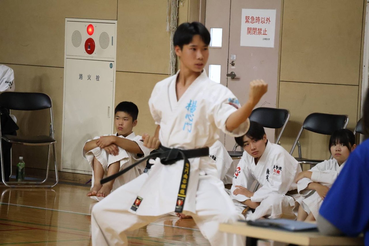 拳を高く構え形を演武する門下生